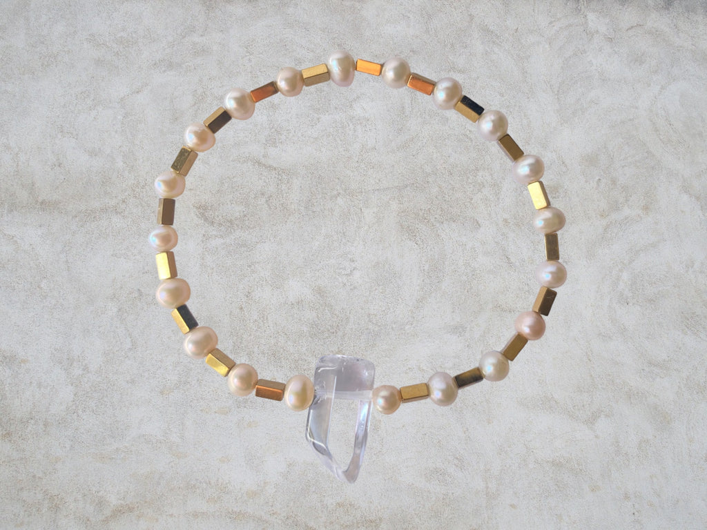 bracelet en petite perle a tendance rosée et petit tube carré en hematite. au milieu une petit cristal de roche 